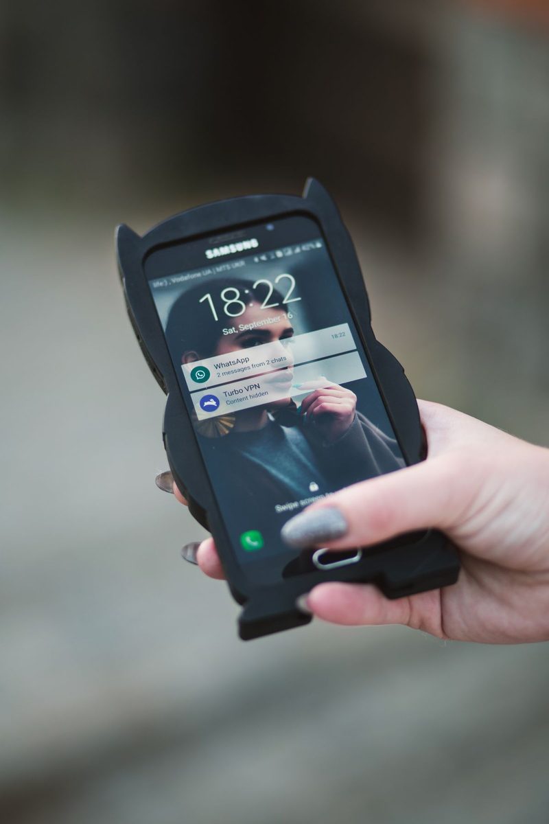 Hand holding a Samsung phone whose lock screen shows the time and two notifications, one with its content hidden
