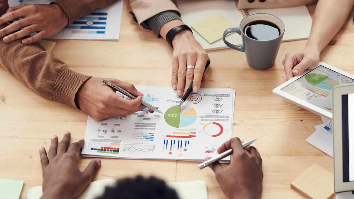 Overhead view of hands pointing at charts and notes during a collaborative meeting