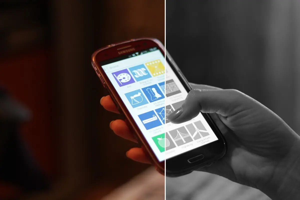 A hand holding an Android phone with colorful app tiles, left half in color and right half in grayscale
