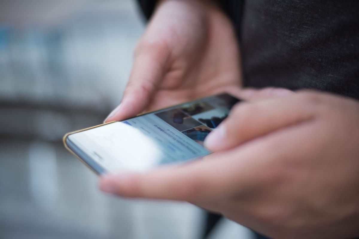 Close-up of two hands holding a smartphone and scrolling with a thumb