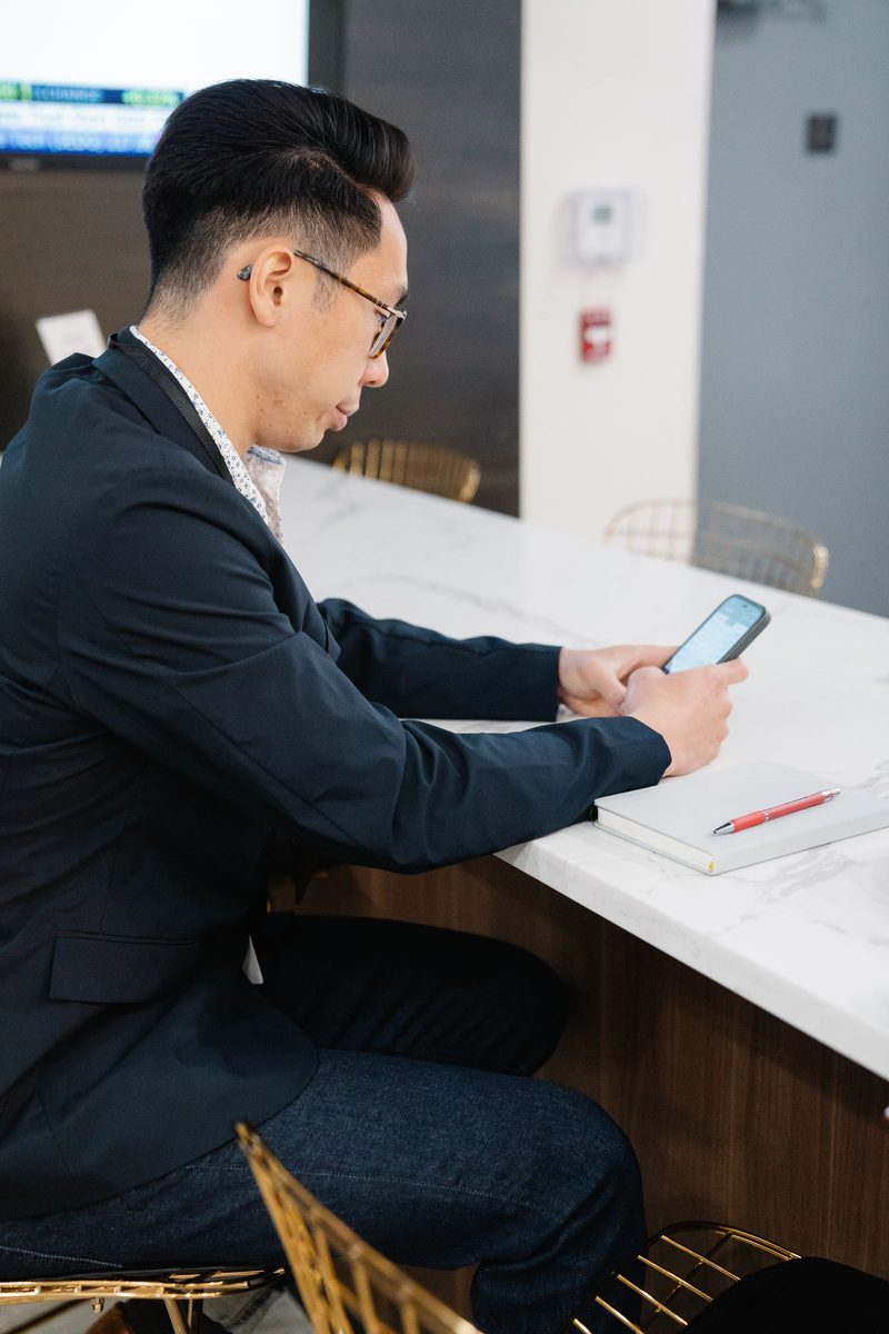 Person seated at a marble office desk looking at a smartphone