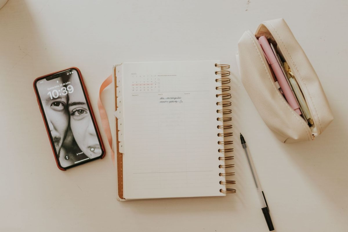 Organized desk with a paper planner, smartphone, and workspace accessories