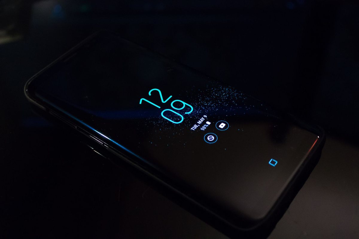 An Android phone lying in the dark with its always-on display showing only the time and date